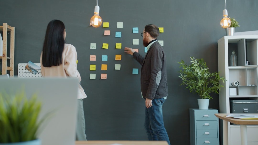 Two people planning with sticky notes on wall