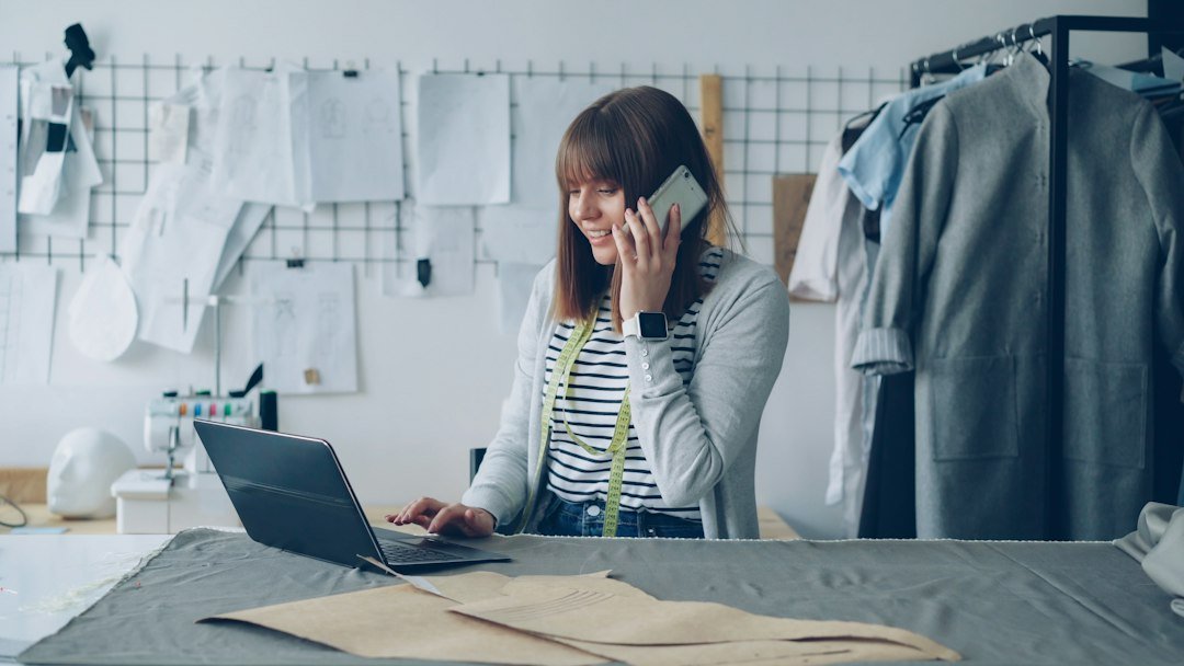 Fashion designer works on laptop while talking on phone