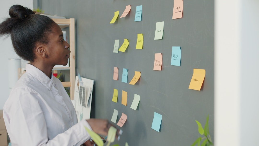 Young woman reviewing colorful sticky notes on wall