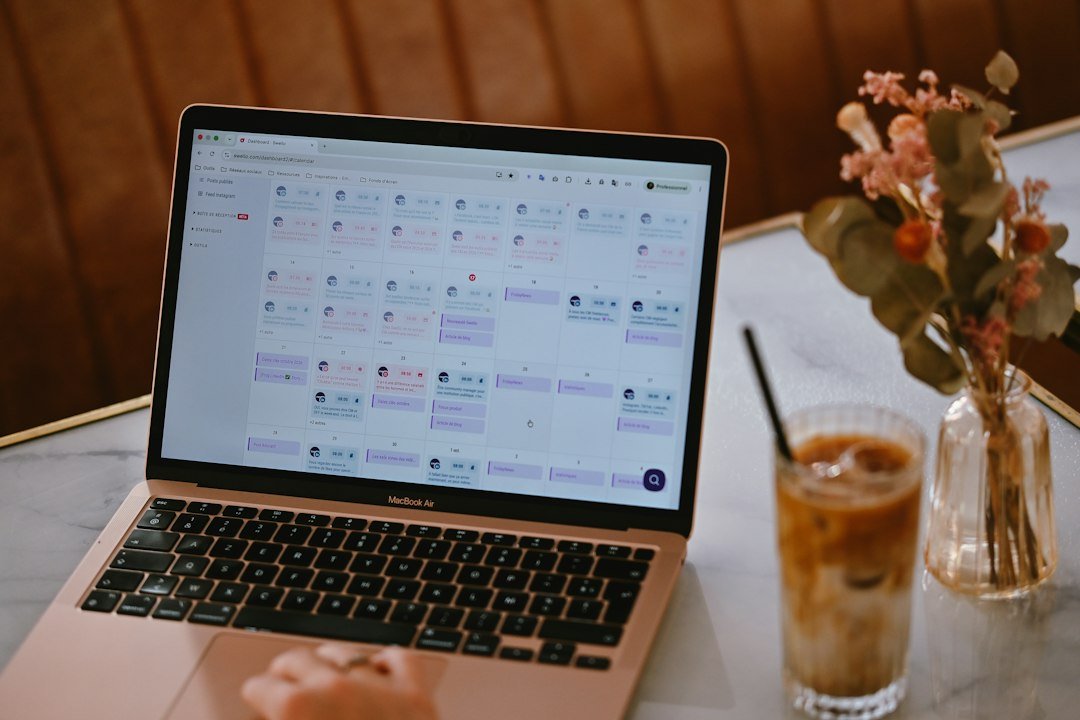 A laptop displaying a social media content calendar beside a glass of iced coffee